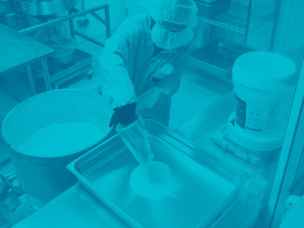 An operator scooping CBD Isolate into a tray for packaging.